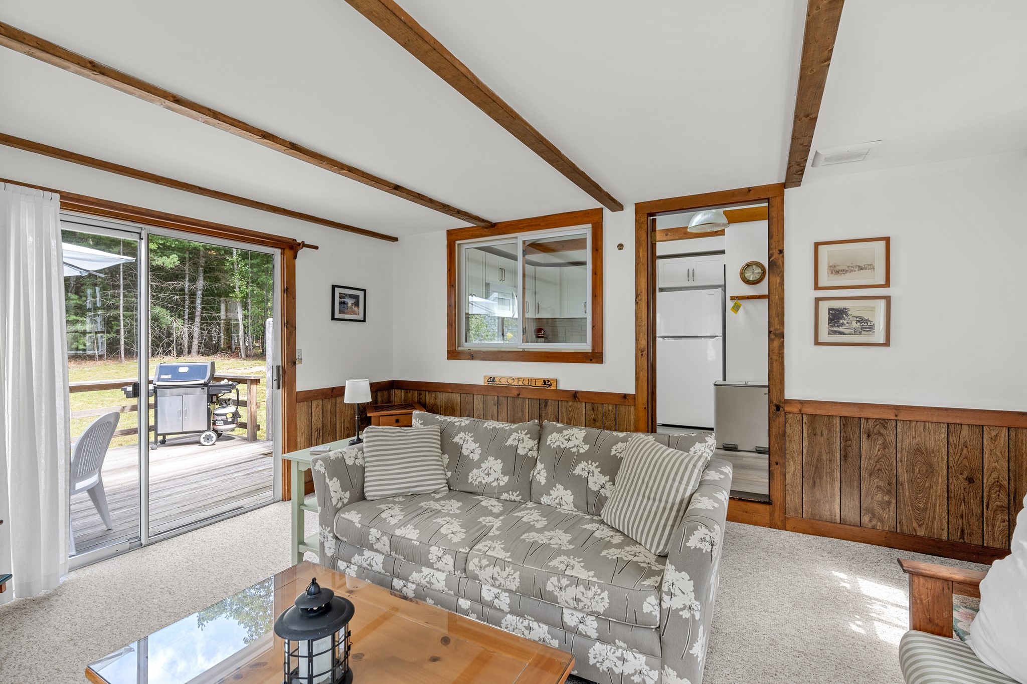 Living room with exposed wood beams, a floral sofa, and sliding doors to a deck.