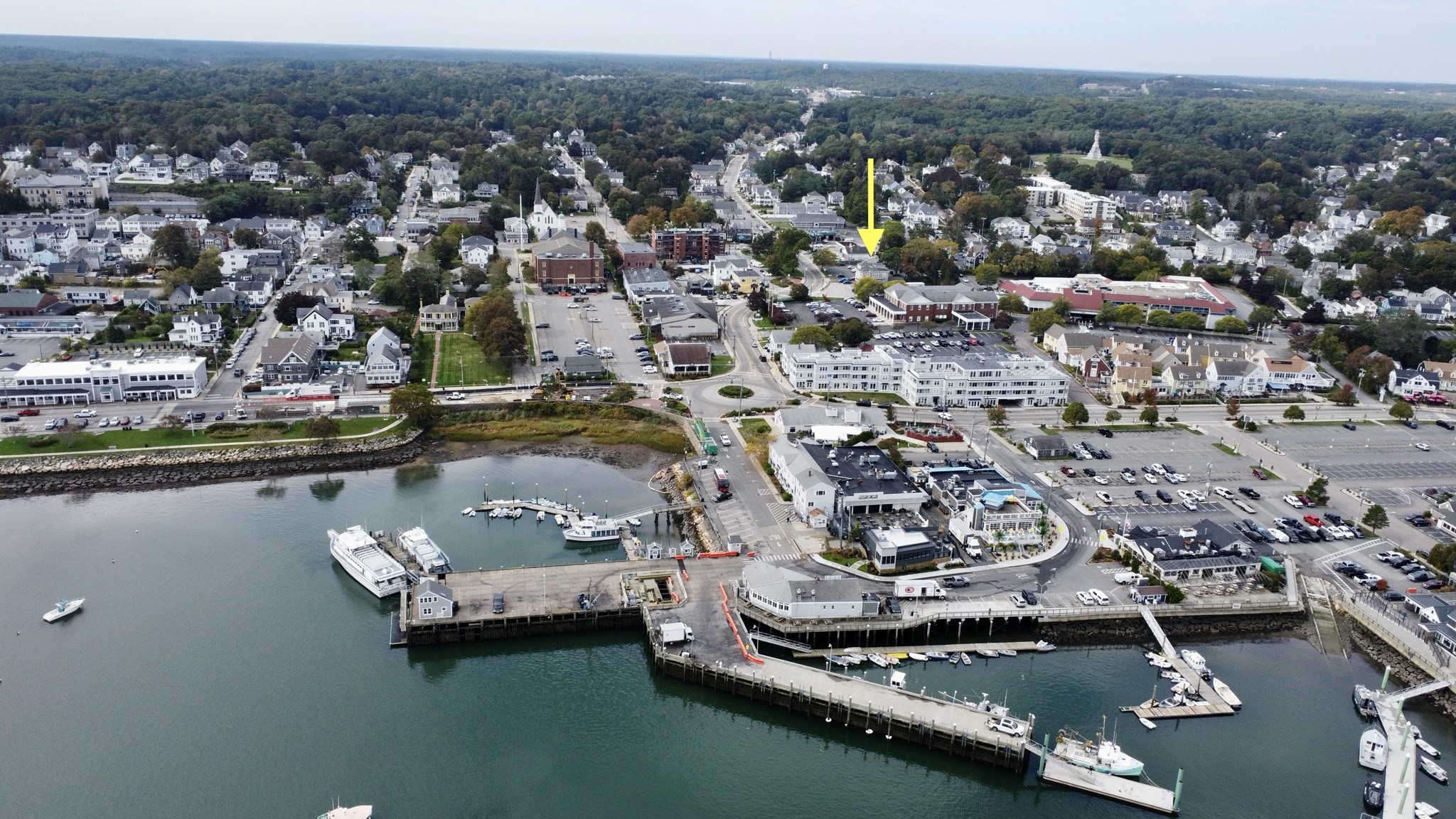 Aerial view of the marked downtown property beside a harbor, marina, and waterfront buildings.