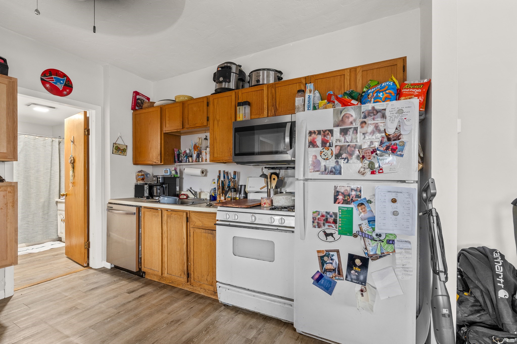Kitchen with honey-colored cabinets, white appliances, and a refrigerator covered in photos and notes.
