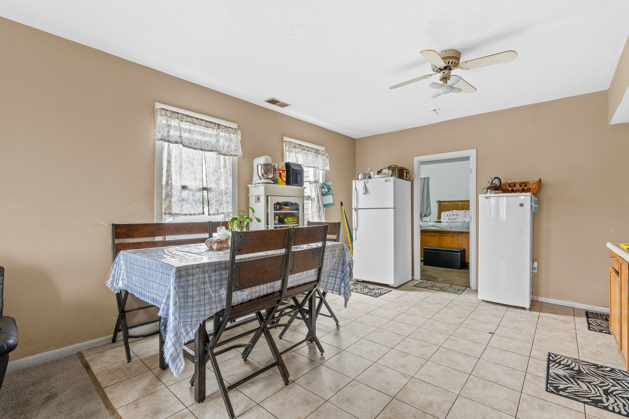 Kitchen dining area with a tiled floor, dining table, and two refrigerators.