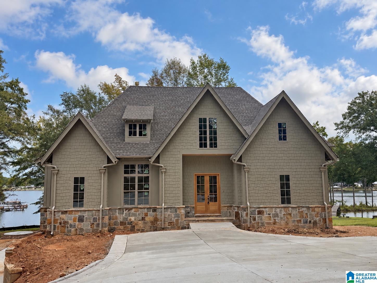 Lakefront home with a stone foundation, three front gables, and a wide concrete driveway.