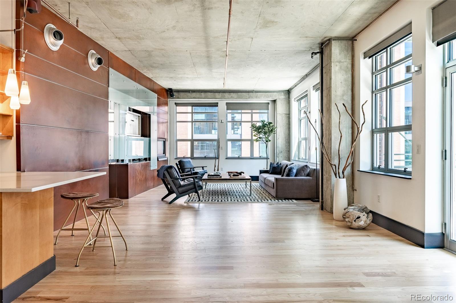 Loft living room with exposed concrete ceiling, expansive windows, and gray sofa