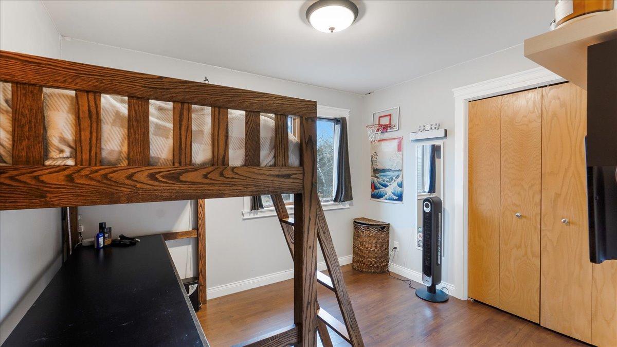 Bedroom with a dark wood loft bunk bed, desk, and small basketball hoop.