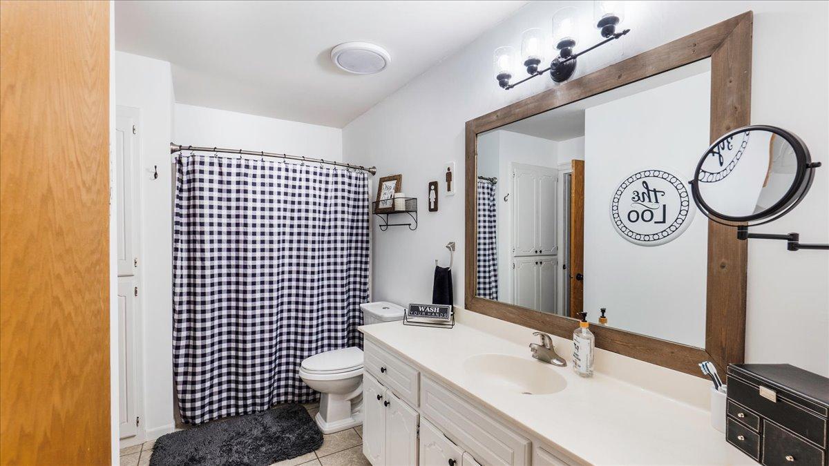 Bathroom with a long white vanity, wood-framed mirror, and black-and-white checkered shower curtain.