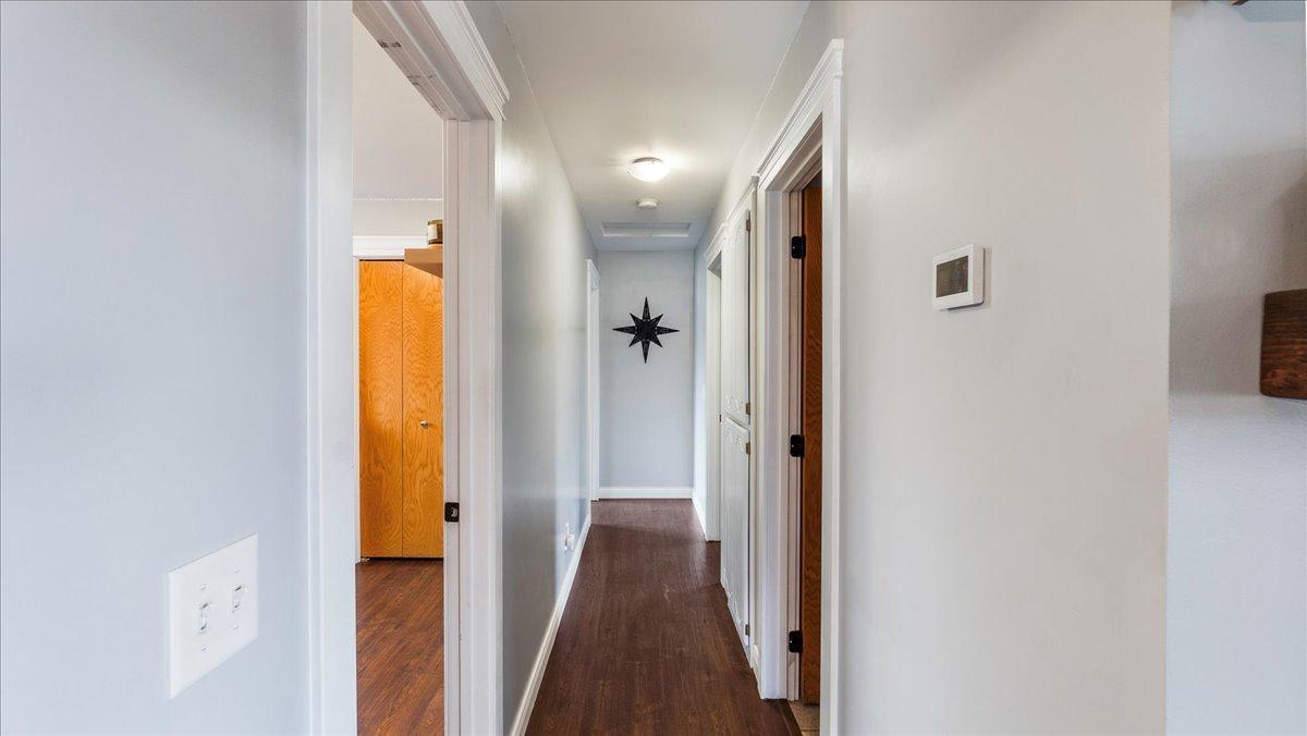 Hallway with dark wood flooring, white trim, and a black star decoration on the far wall.