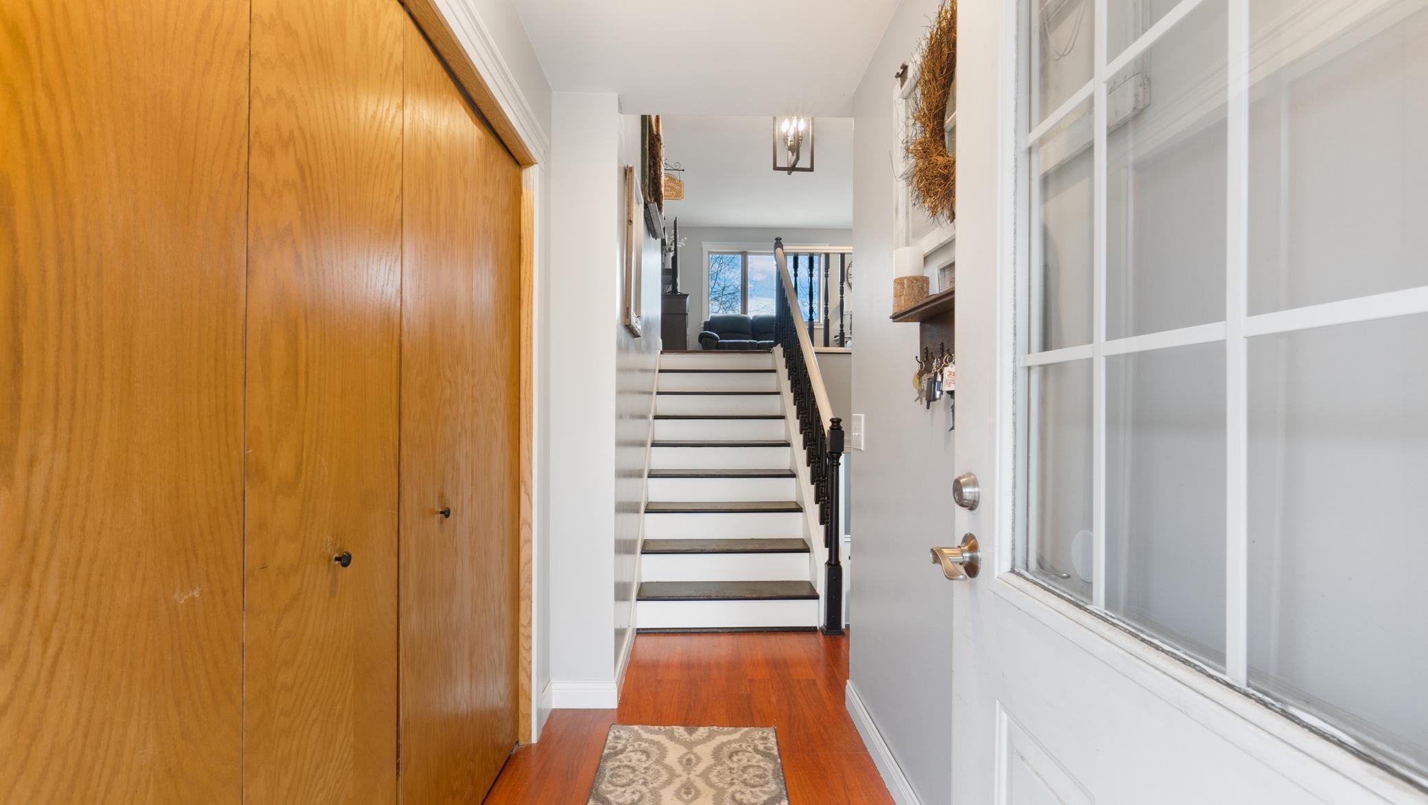 Entry hall with wooden closet doors and a staircase leading to a window-side sitting area.