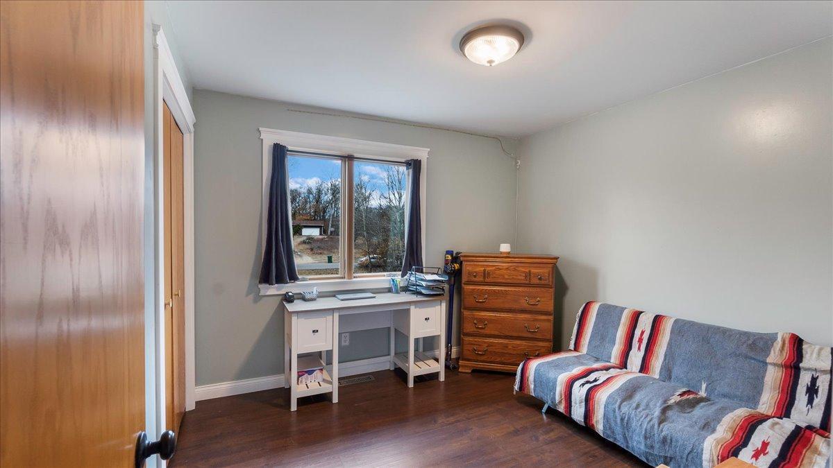 Bedroom with a desk beneath the window and a striped sofa bed.