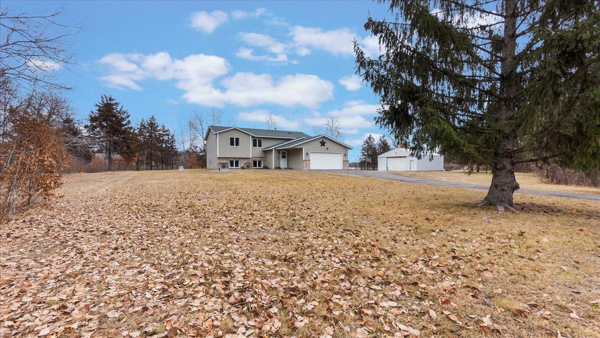 Split-level home and separate outbuilding beyond a broad autumn lawn.