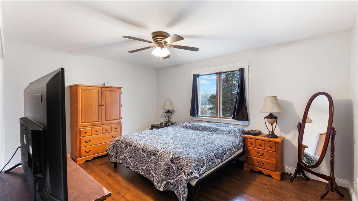 Bedroom with patterned bedding, wooden furniture, and a window framed by dark curtains.