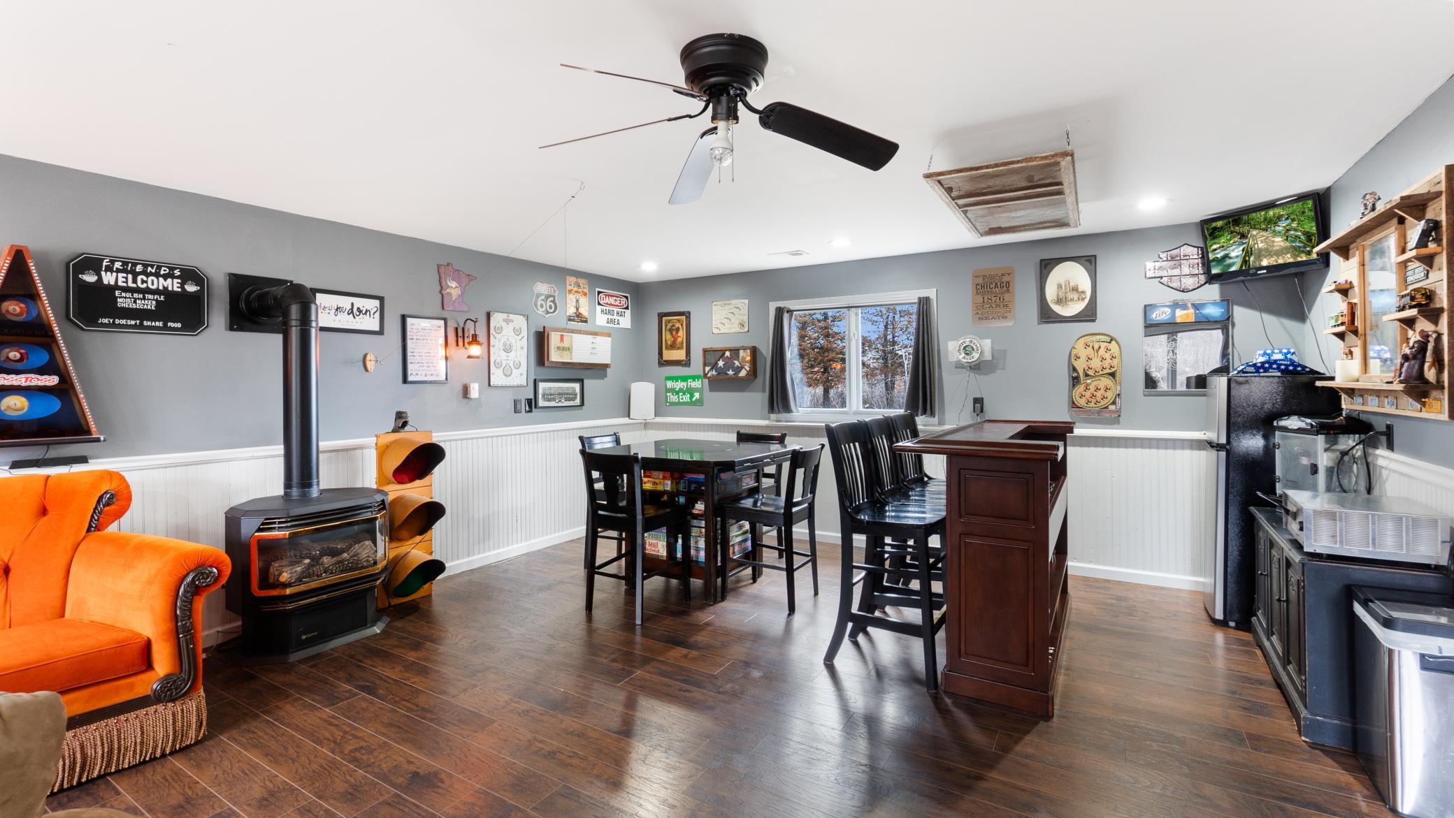 Game room with a pool table, arcade game, wood stove, and orange armchair.