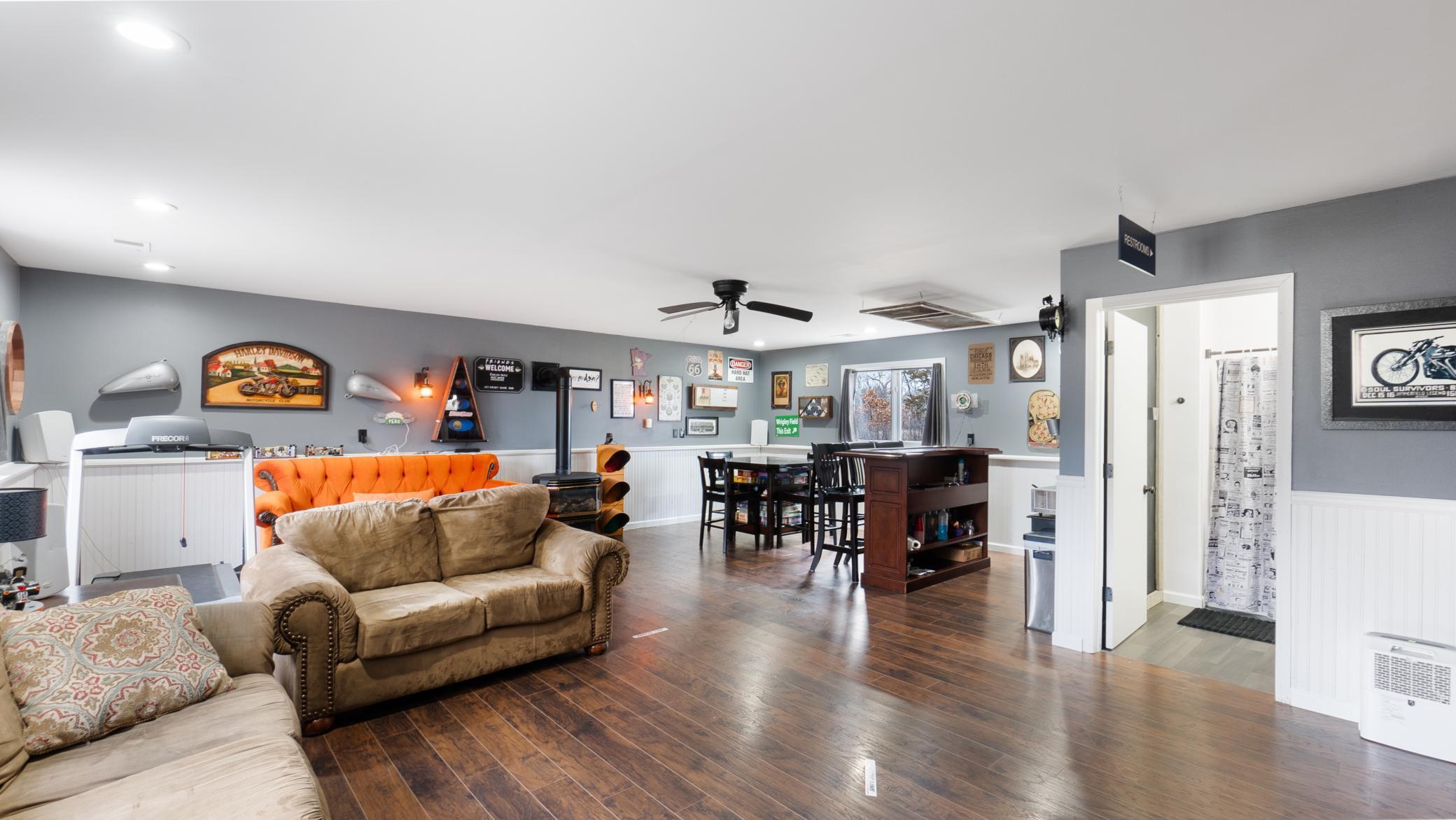 Furnished recreation room with tan and orange sofas, a treadmill, and a game table.