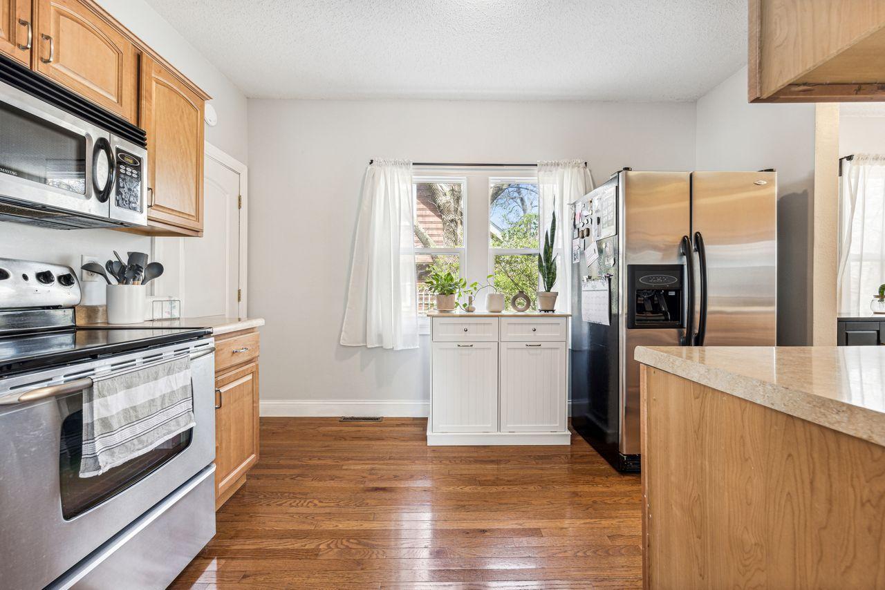 Kitchen with stainless steel appliances, honey-toned cabinets, and hardwood floors.