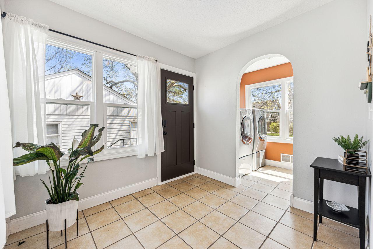 Tiled entryway with a dark front door and an arched opening to the laundry room.