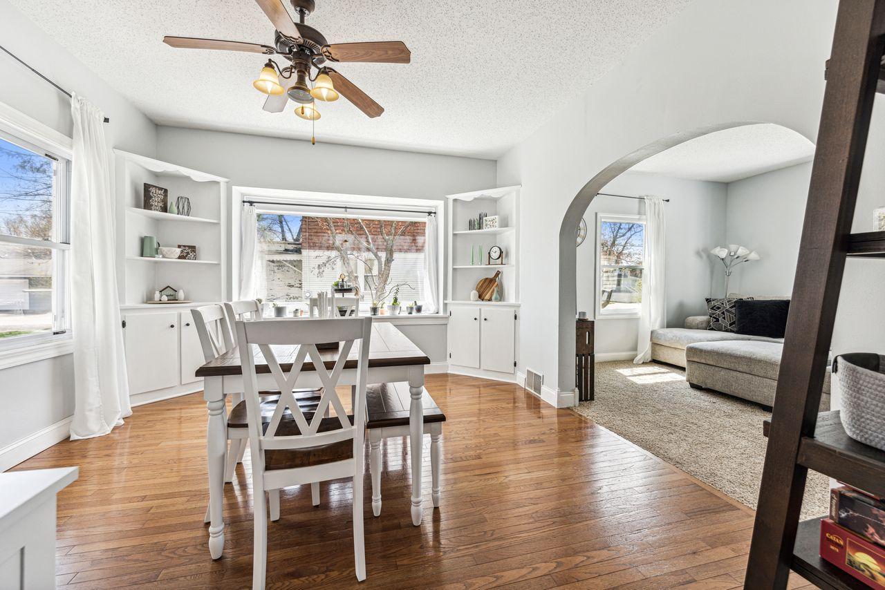 Dining room with built-in shelves, hardwood floors, and an arched opening to the living room.