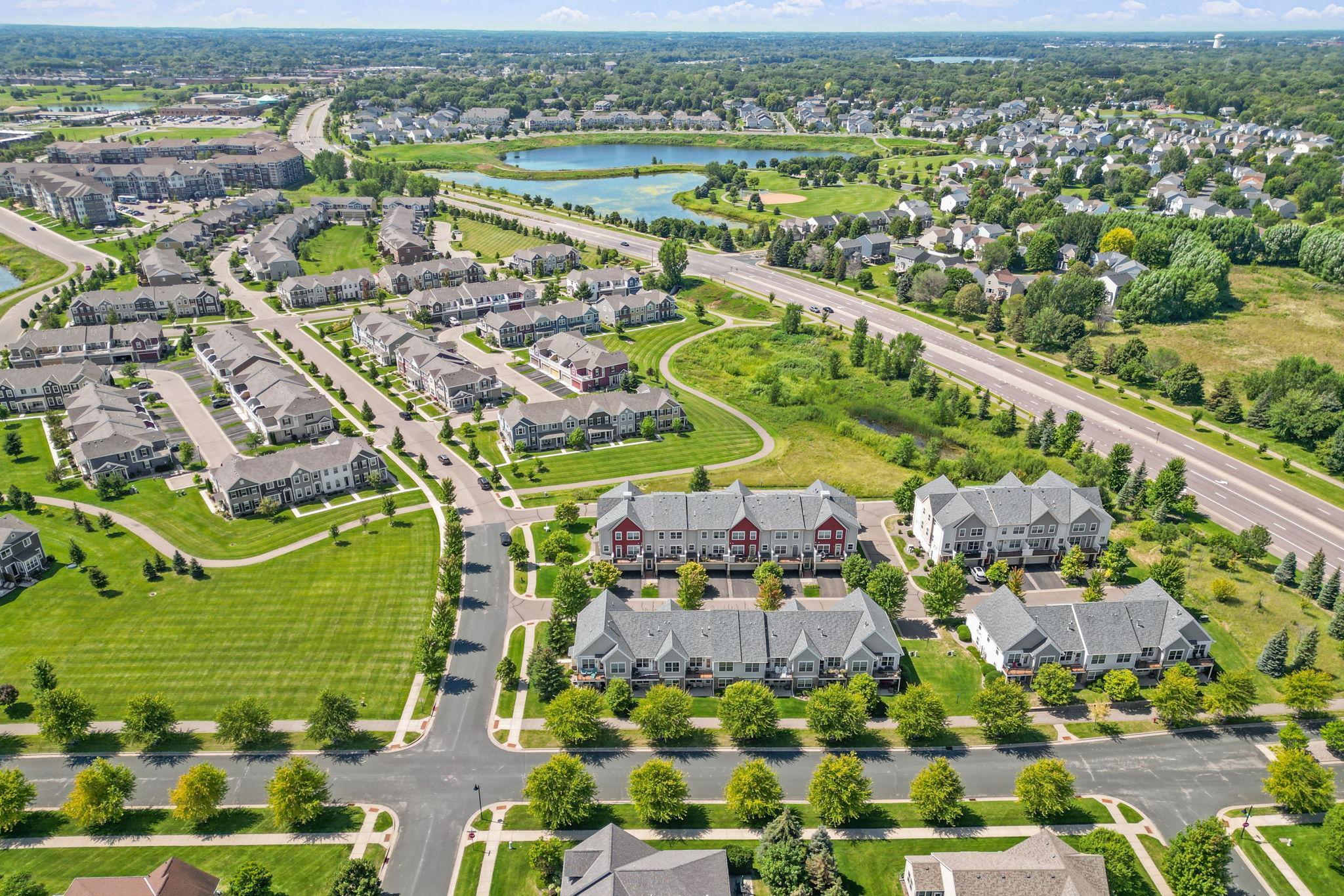 Aerial view of a townhouse community with landscaped lawns, ponds, and walking paths.