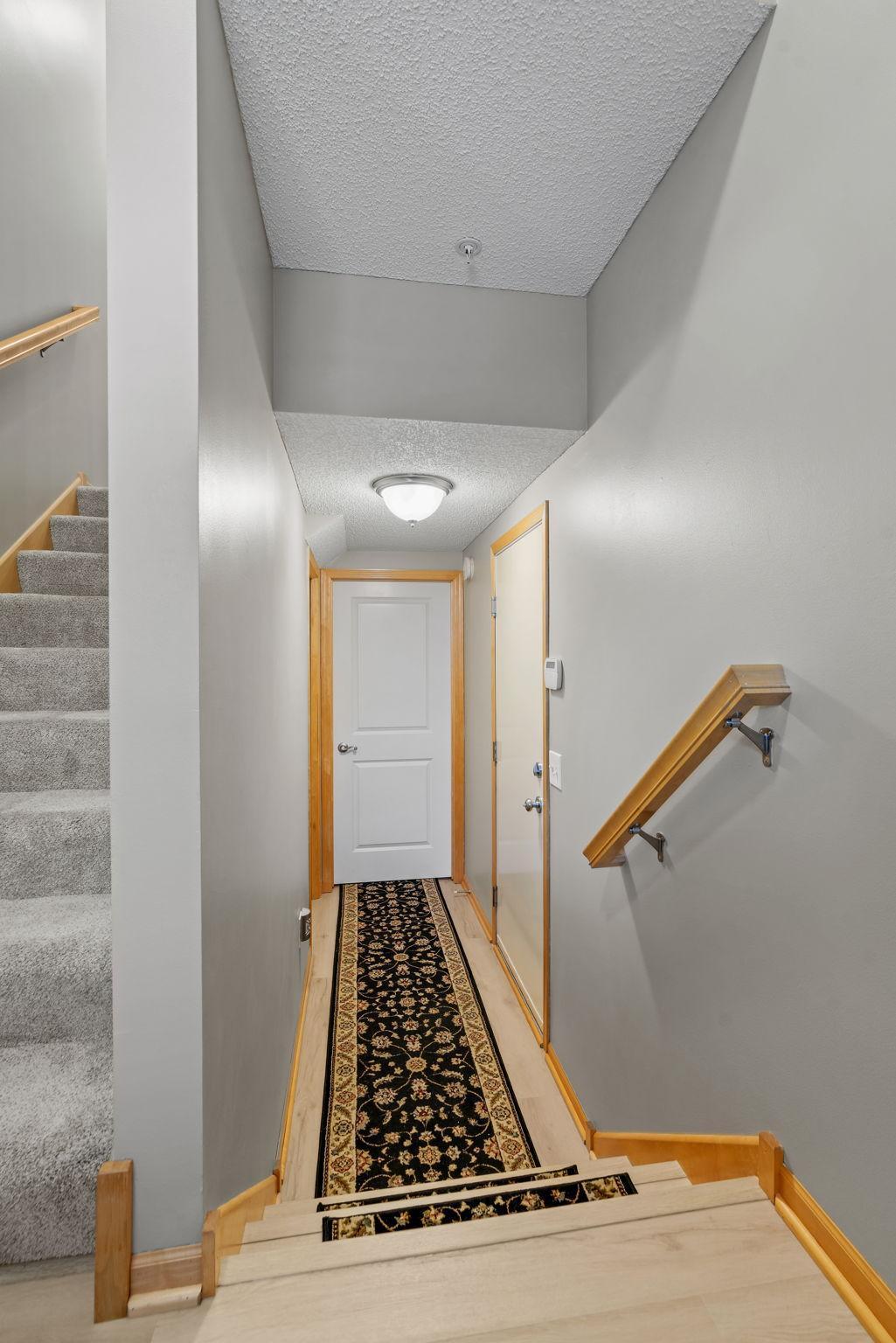 Hallway with carpeted stairs, light wood trim, and a patterned runner.