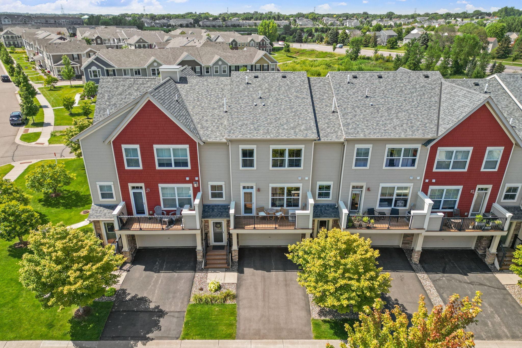 Aerial view of attached townhomes with red gables, private decks, and garages.