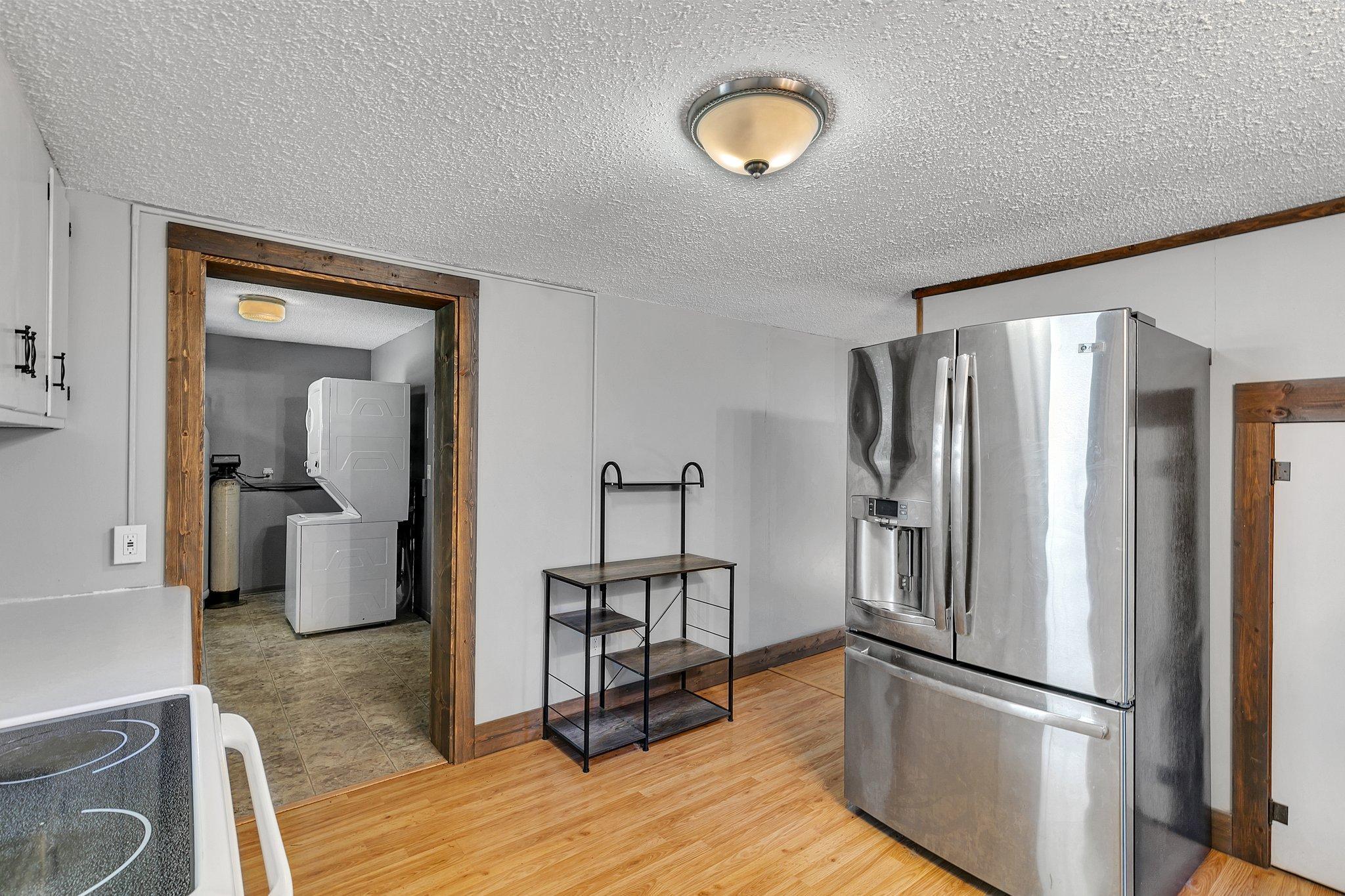 Kitchen with stainless steel refrigerator and wood-trimmed doorway to a laundry room.