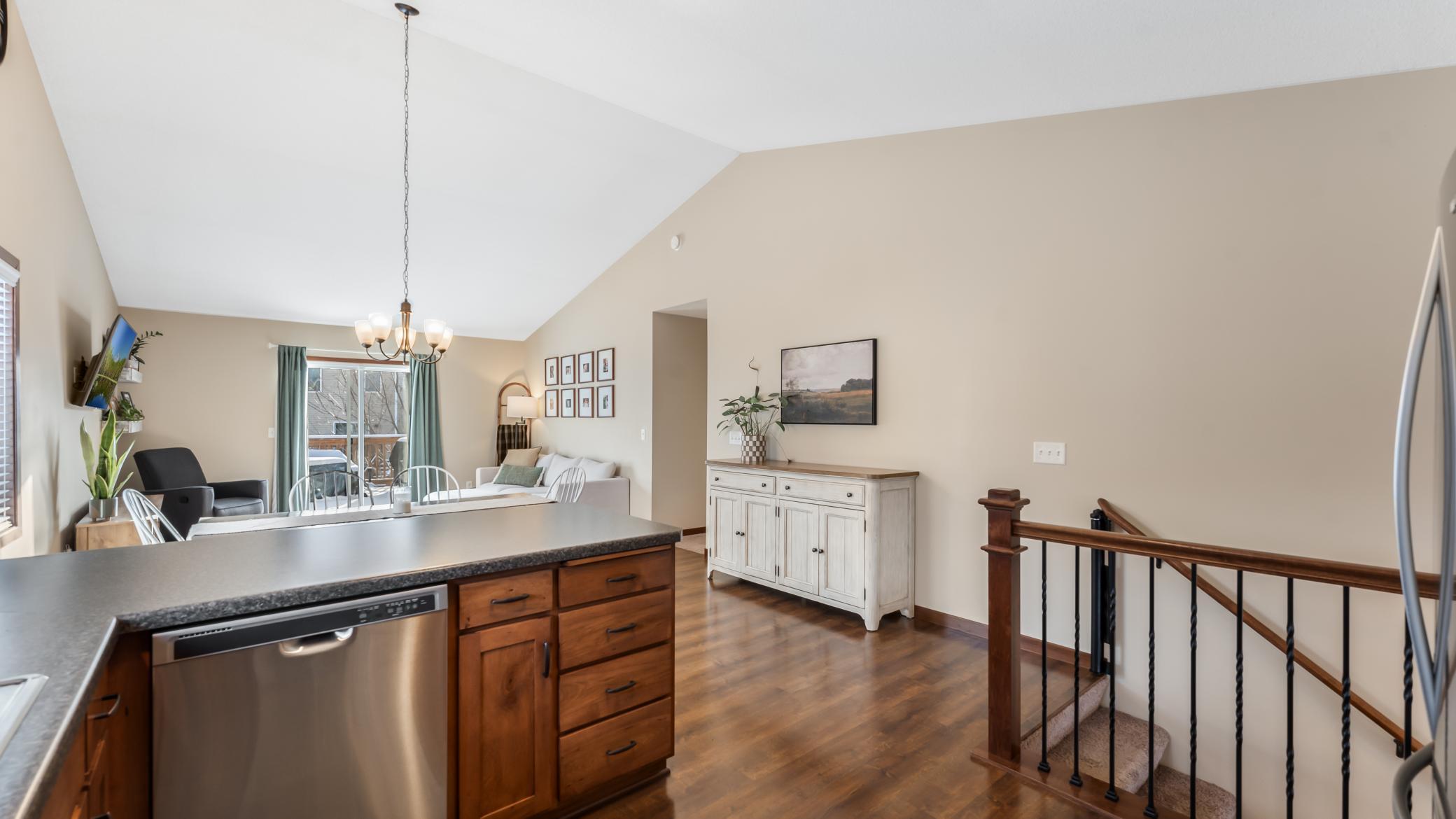 Open-plan kitchen and living area with a wood-topped island, high ceiling, and staircase railing.