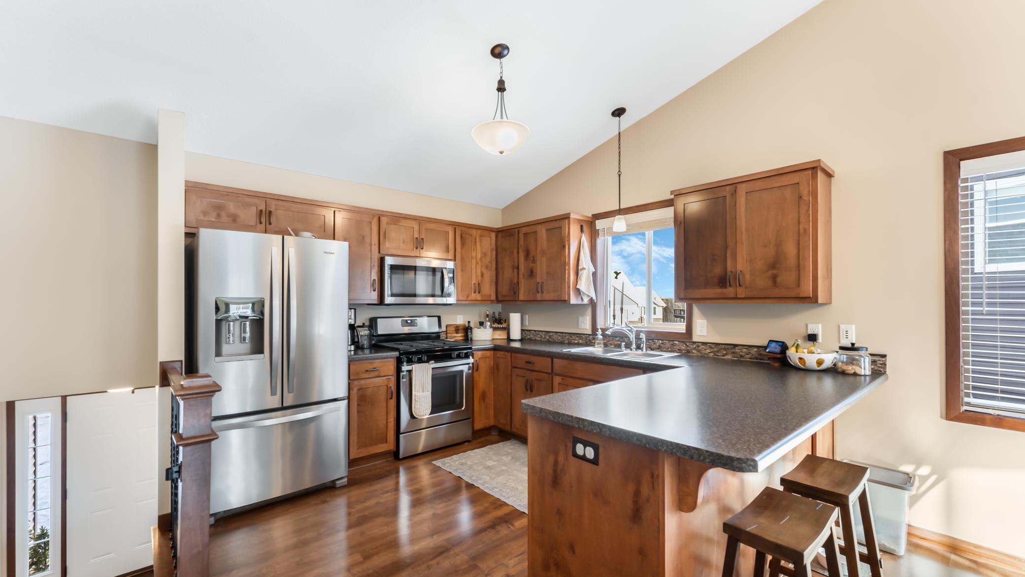Kitchen with wood cabinets, stainless steel appliances, and a large breakfast bar with stools.