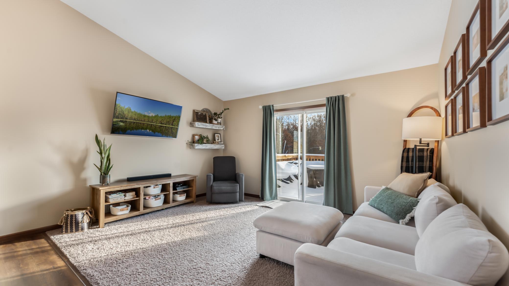 Living room with a white sectional, gray armchair, and sliding door opening to a snowy deck.