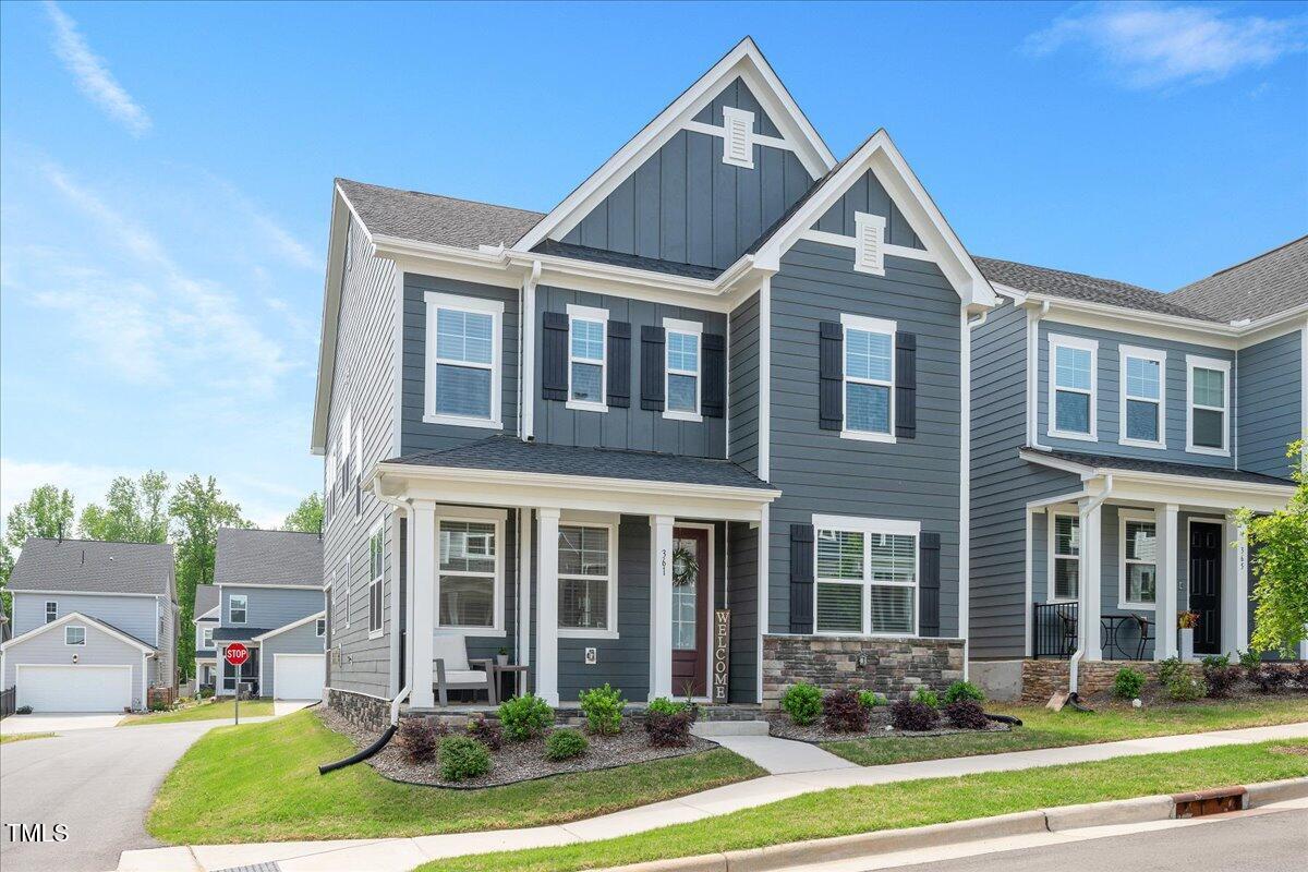 Two-story gray-blue home with prominent gables, dark shutters, and a covered front porch.