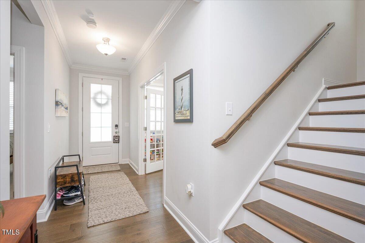 Entry hall with a glass-paneled front door and staircase with dark wood treads.