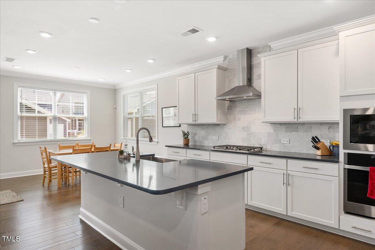 Bright kitchen with a large island, white cabinets, marble-look backsplash, and dining area by the windows.