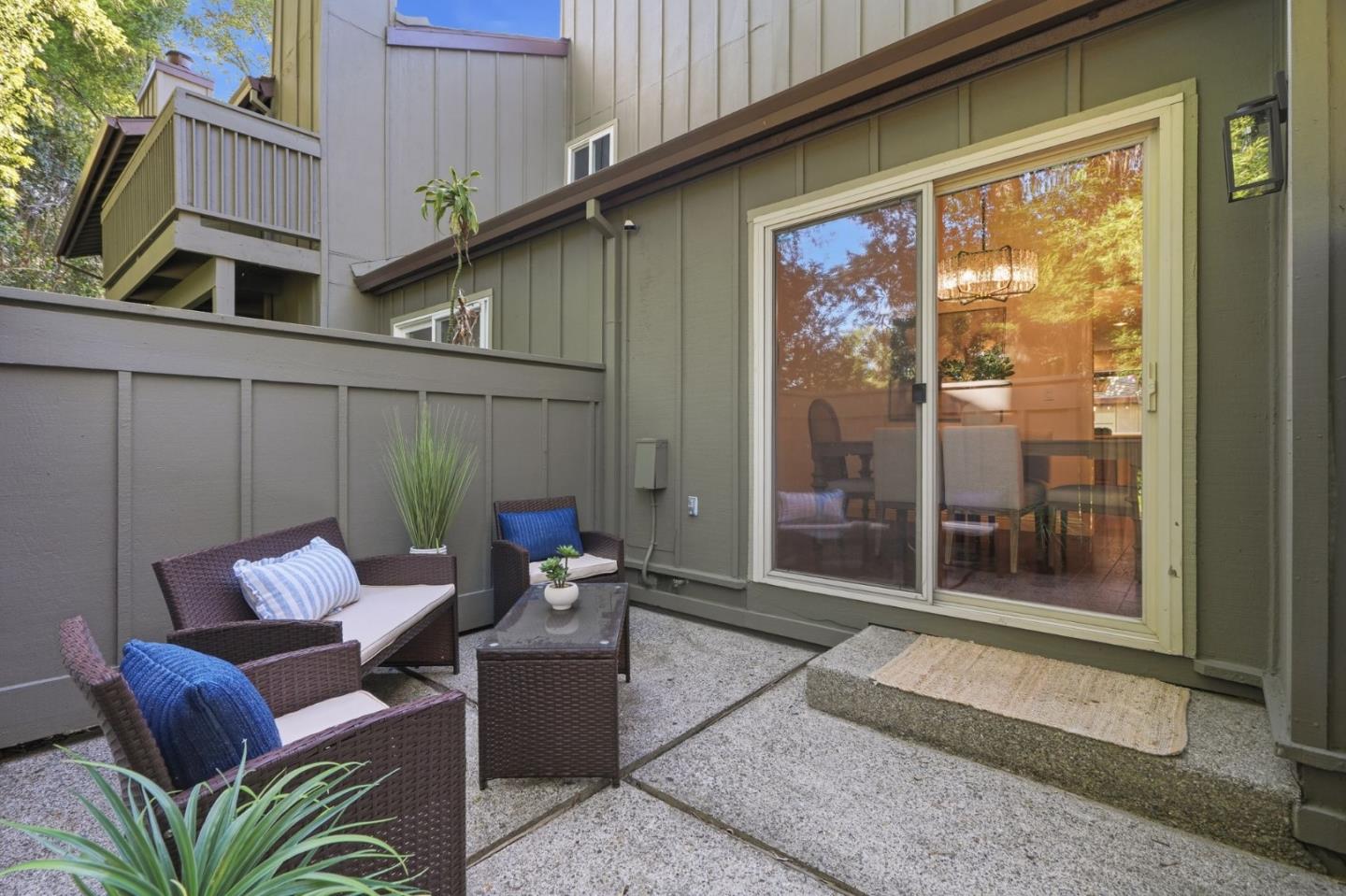 Furnished patio with wicker seating beside sliding glass doors and a fenced courtyard.