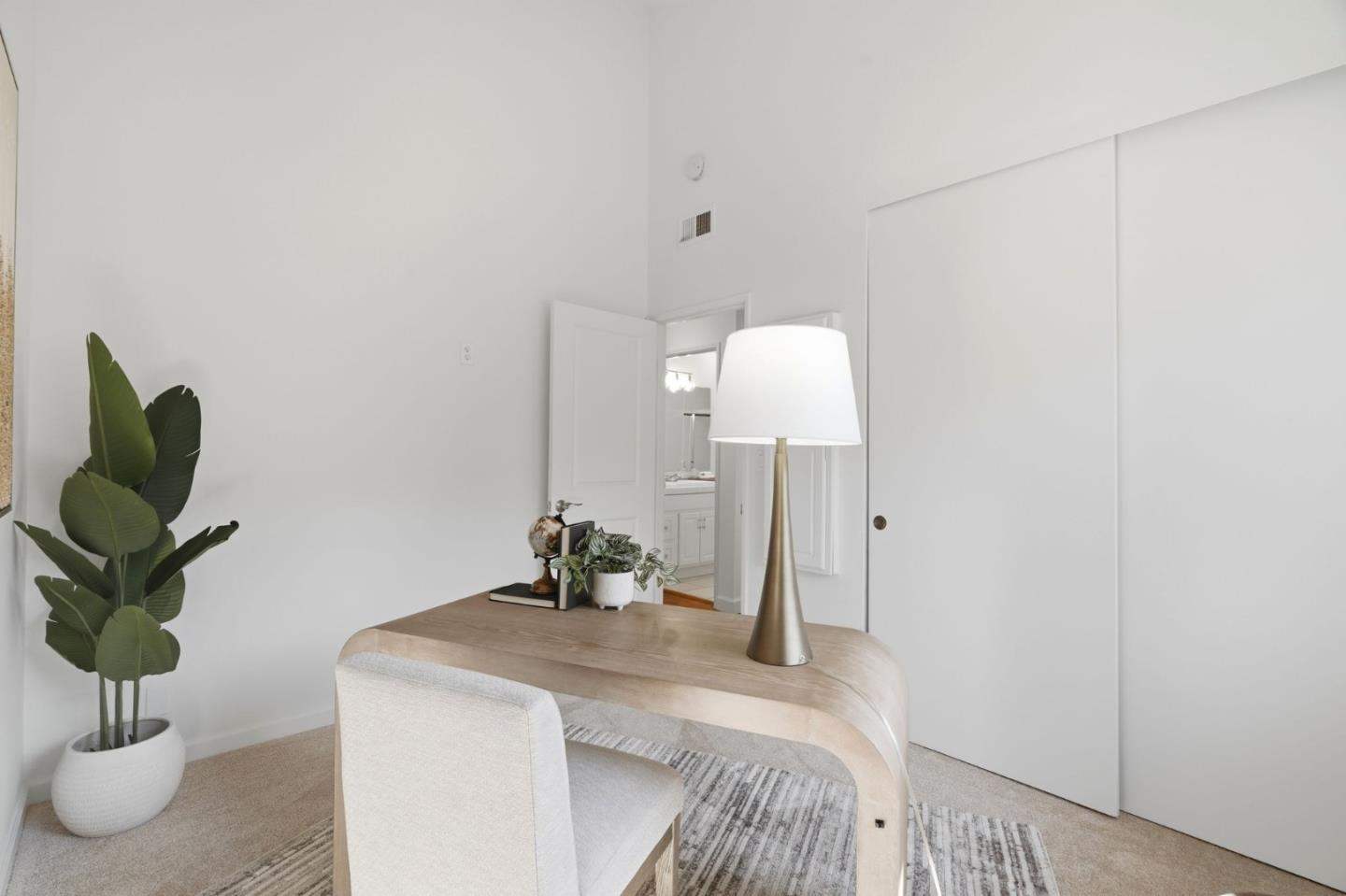 Bright home office with a curved wood desk, white chair, and large potted plant.