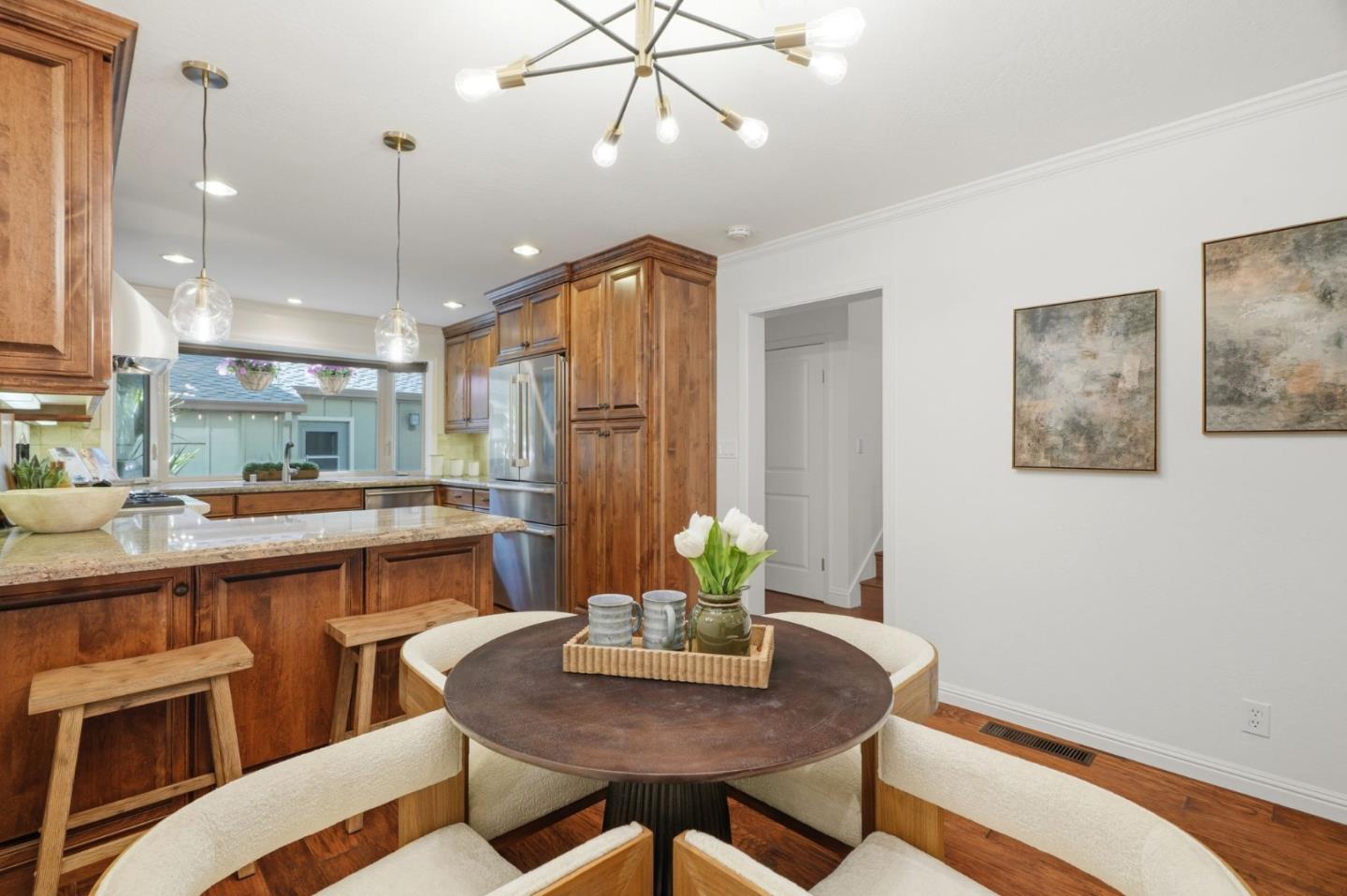 Kitchen and dining area with warm wood cabinets, granite counters, and a round table with curved seating.