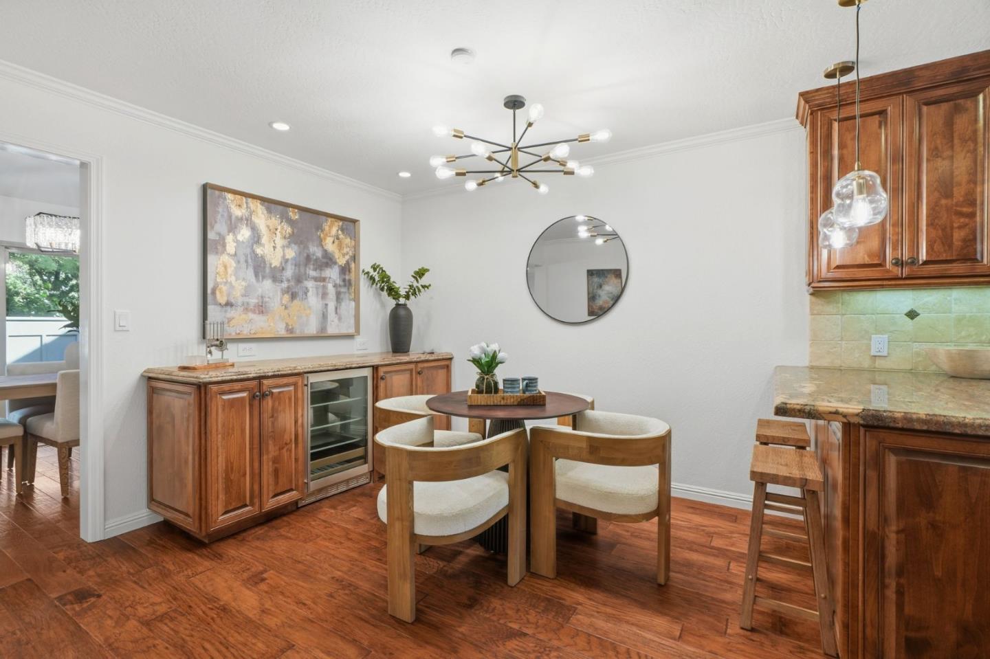 Dining area with a round table, wood chairs, rich cabinetry, and hardwood floors.