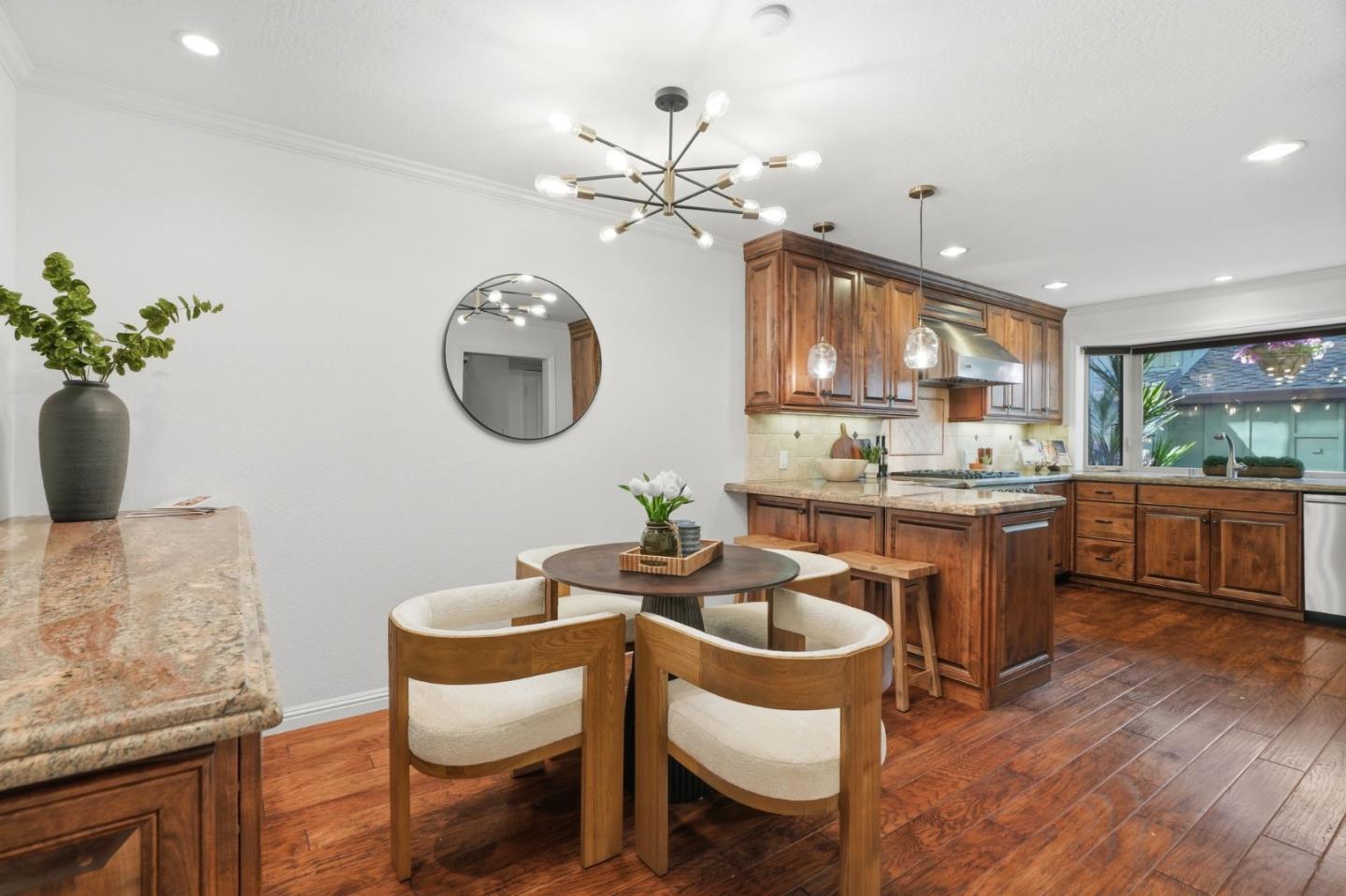 Kitchen and dining area with warm wood cabinets, hardwood floors, and a round table with upholstered chairs.