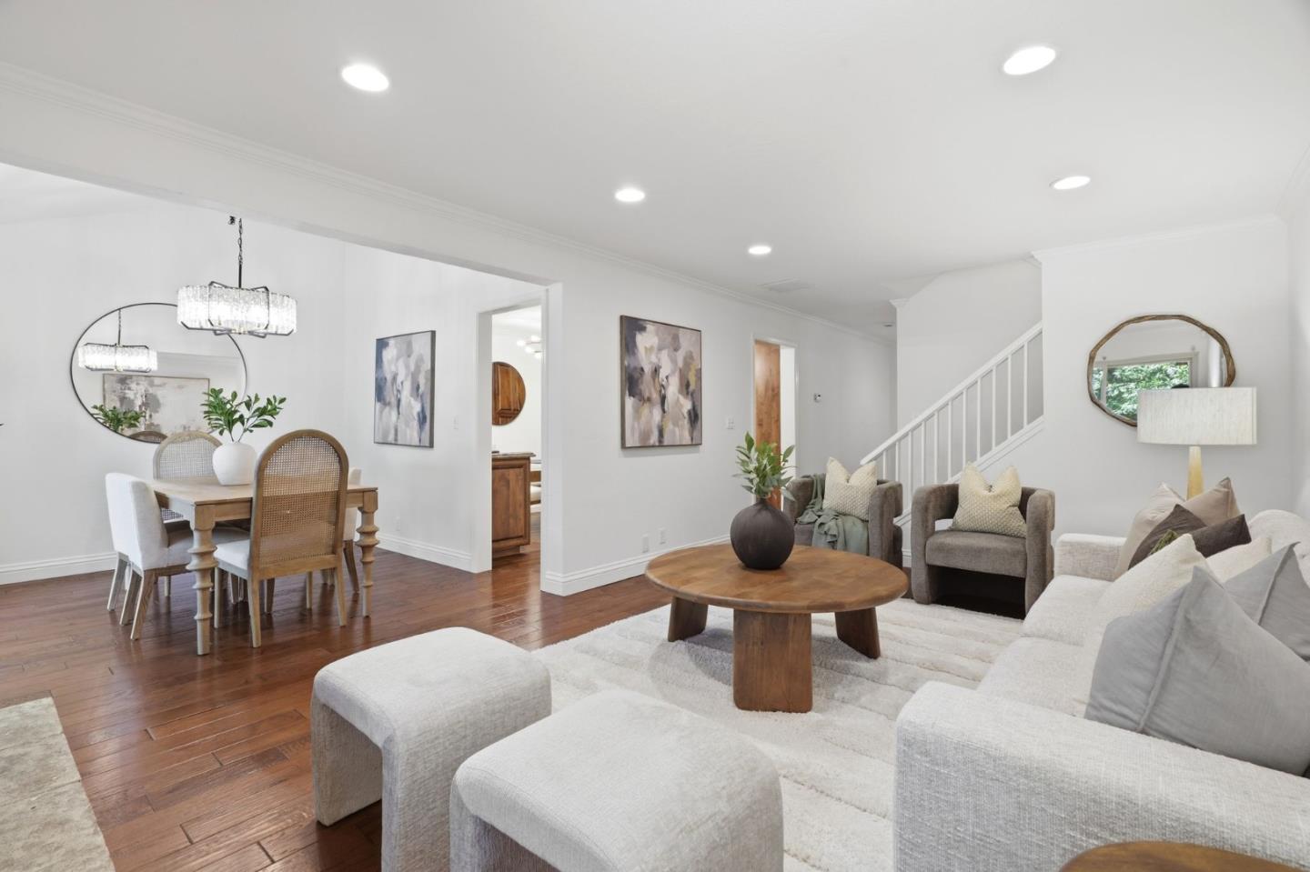 Staged living room with a white sectional, round wood coffee table, and adjoining dining area.
