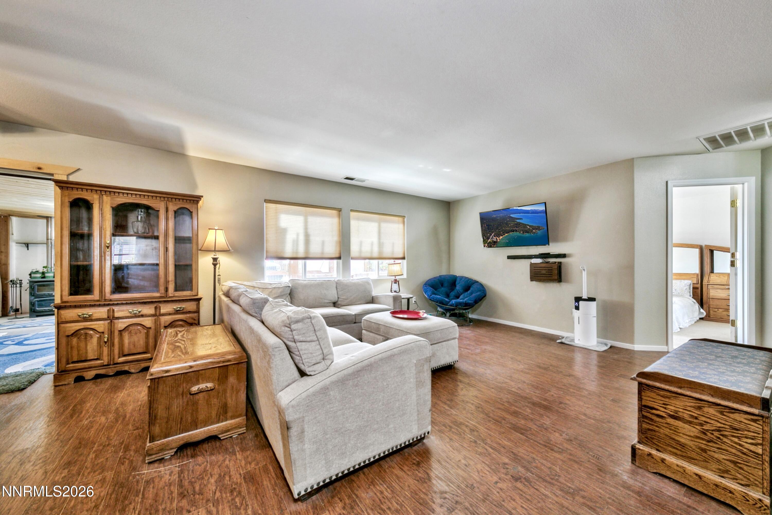 Furnished living room with hardwood floors, a gray sectional, and a large wooden display cabinet.