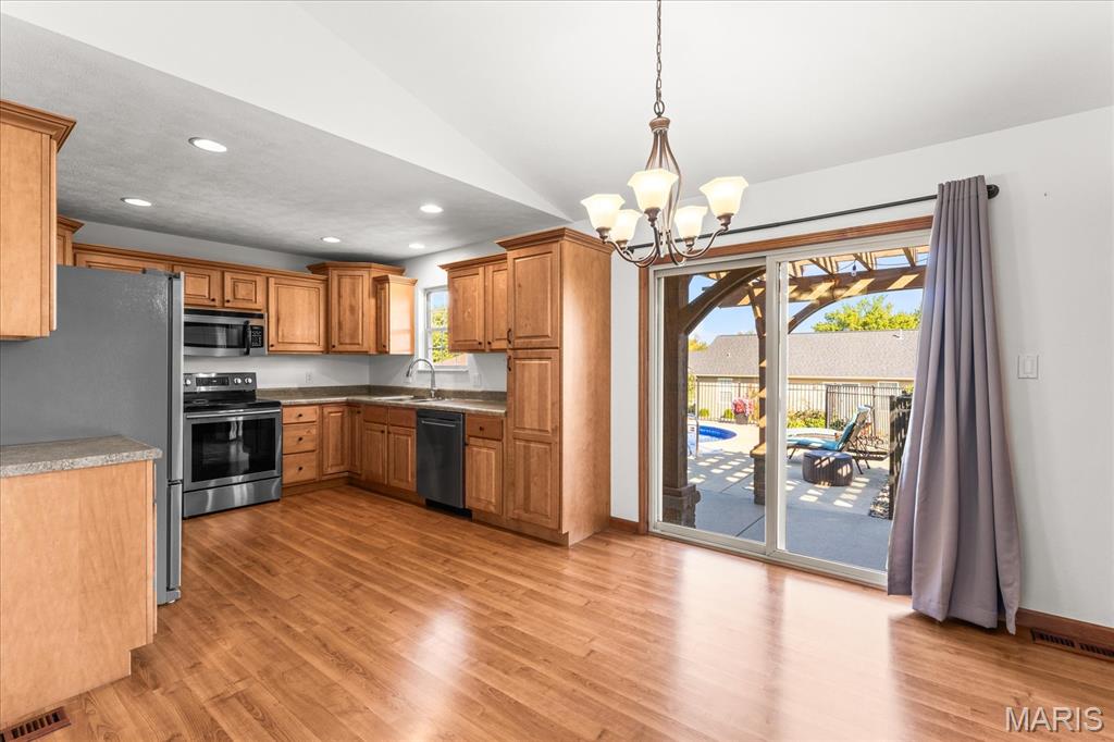 Kitchen with wood cabinets and stainless steel appliances beside a sliding door to the patio.