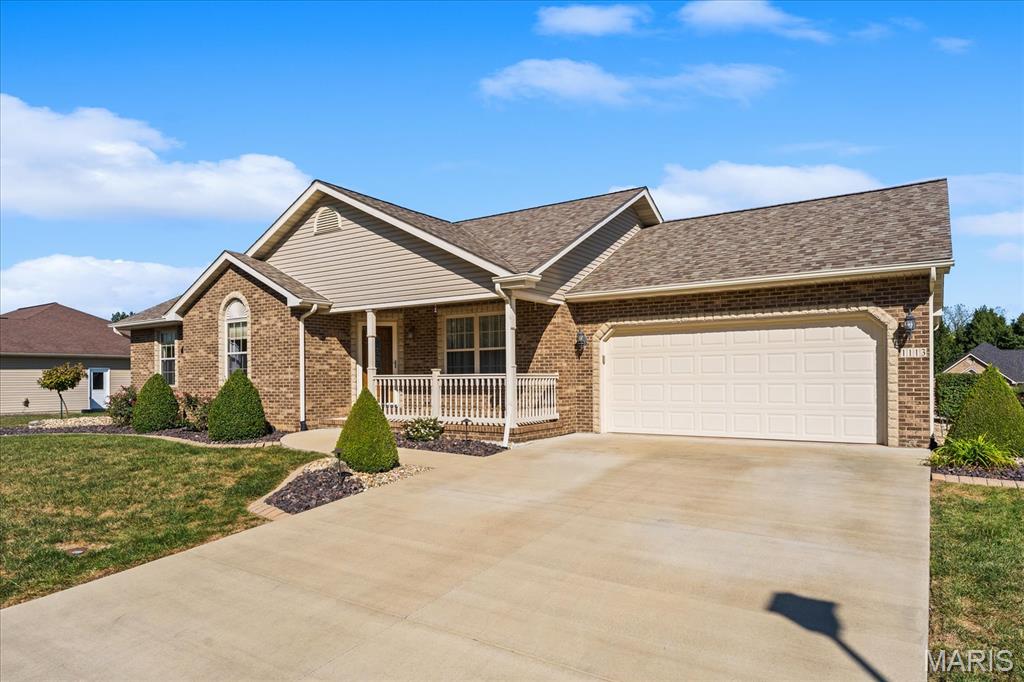Brick home with a covered porch, attached two-car garage, and wide concrete driveway.