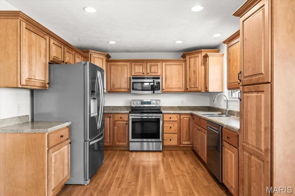 Kitchen with light wood cabinets, stainless steel appliances, granite countertops, and wood flooring.