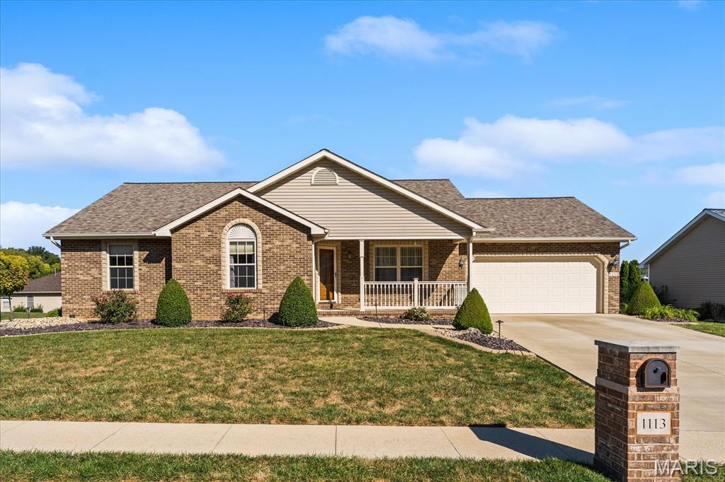 Brick home with covered porch, attached garage, landscaped lawn, and mailbox marked 1113.