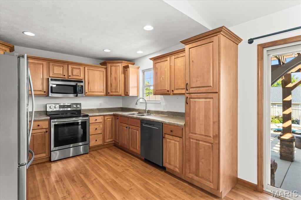 Kitchen with wood cabinets and stainless steel appliances, opening onto a deck.