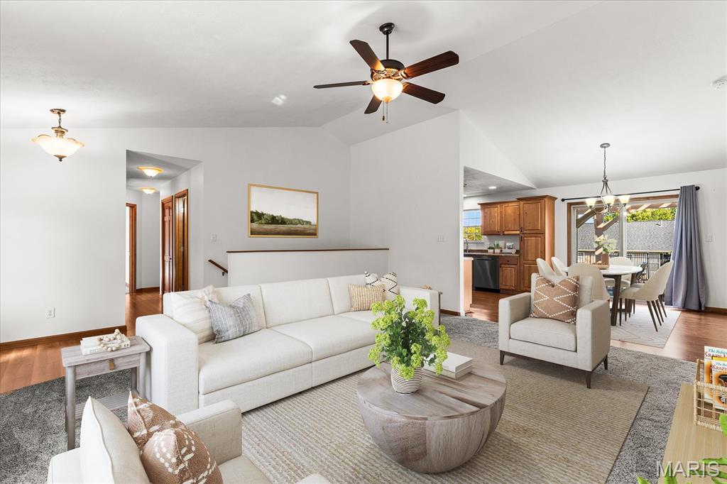 Open-plan living room with a white sectional, dining area, and kitchen opening to a fenced outdoor space.
