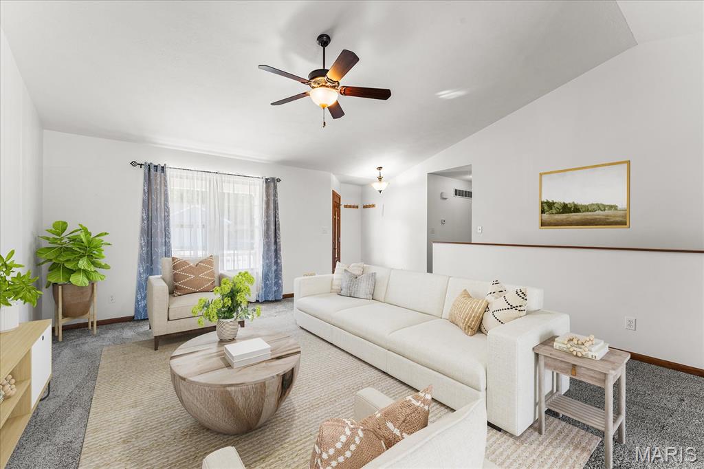 Living room with white sofas, a round wood coffee table, and a ceiling fan.