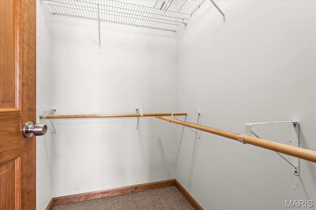 Walk-in closet with wooden hanging rods and overhead wire shelving.