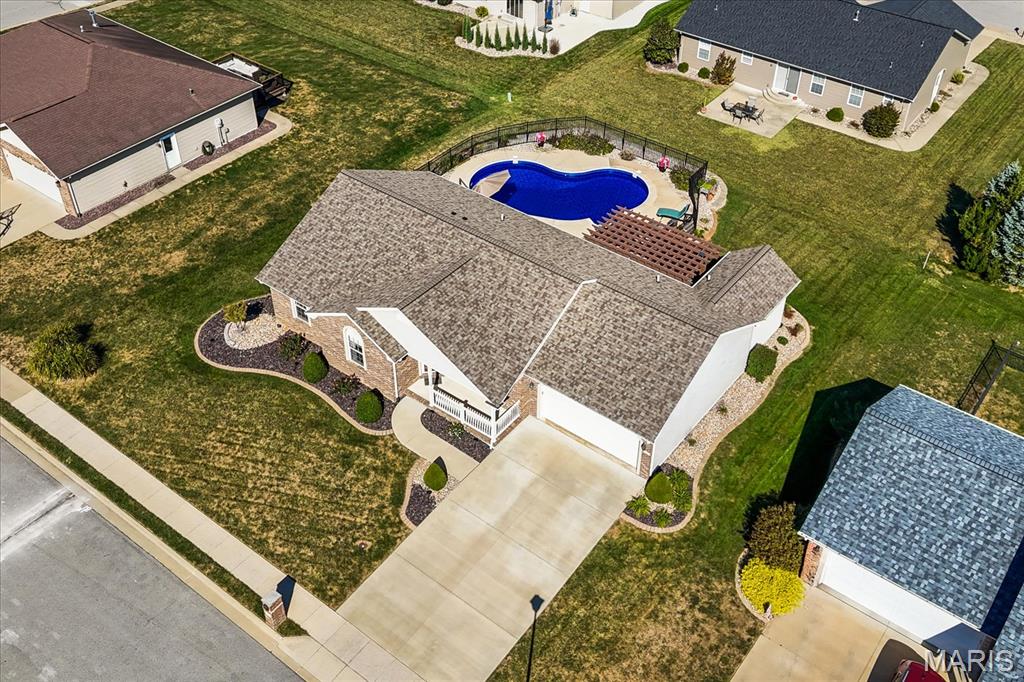 Aerial view of a brick home with a wide driveway and fenced backyard pool.