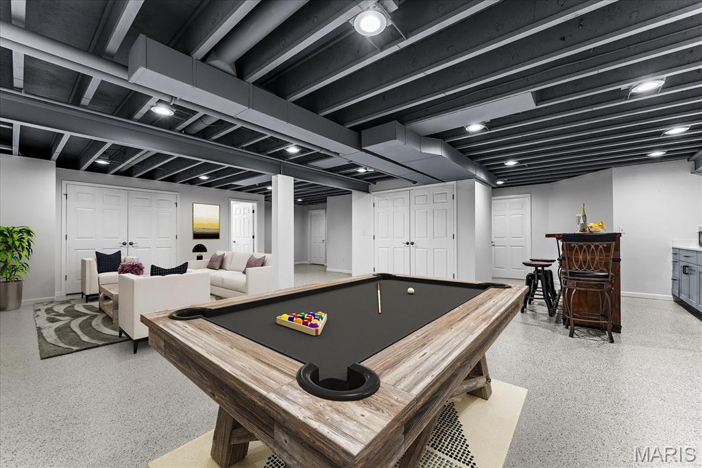 Finished basement recreation room with a pool table, white sofa seating area, and small bar.