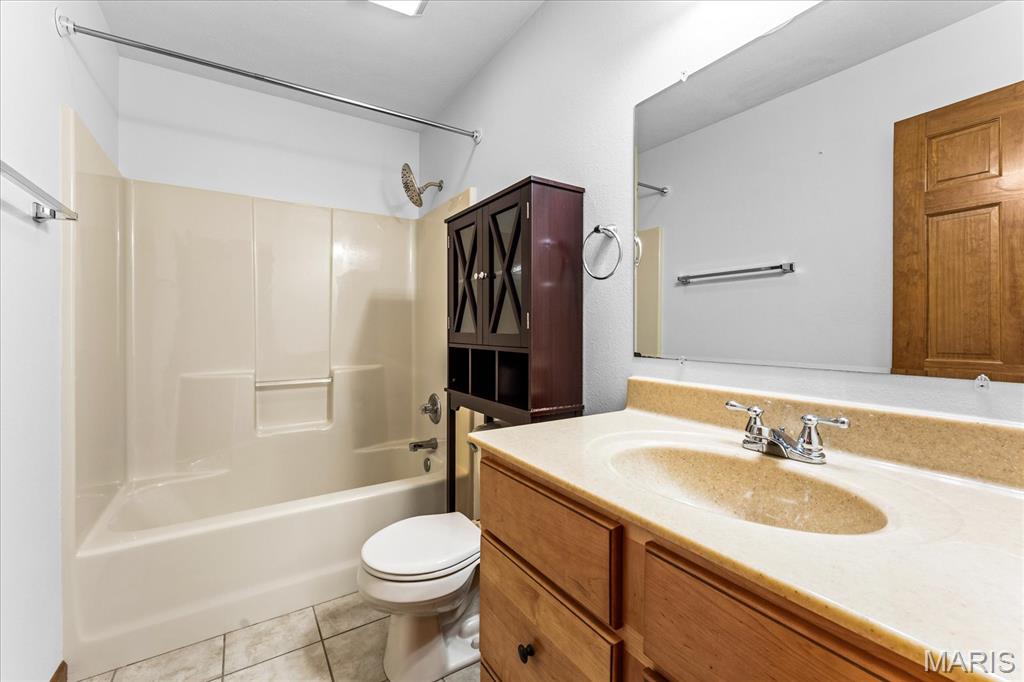 Bathroom with a tub and shower, wood vanity, large mirror, and dark storage cabinet.