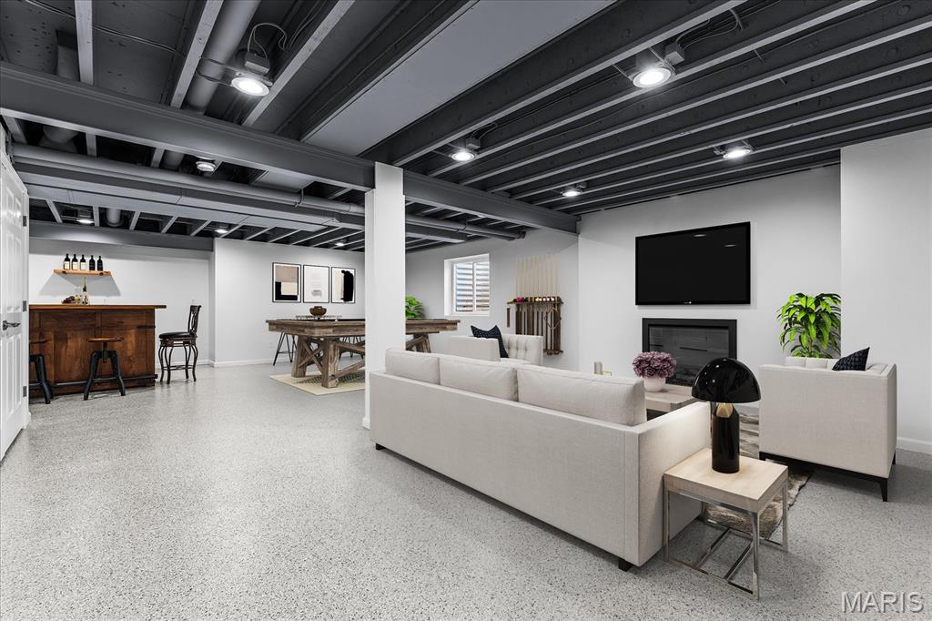 Finished basement living area with white seating, a fireplace, and a wood bar beneath an exposed ceiling.
