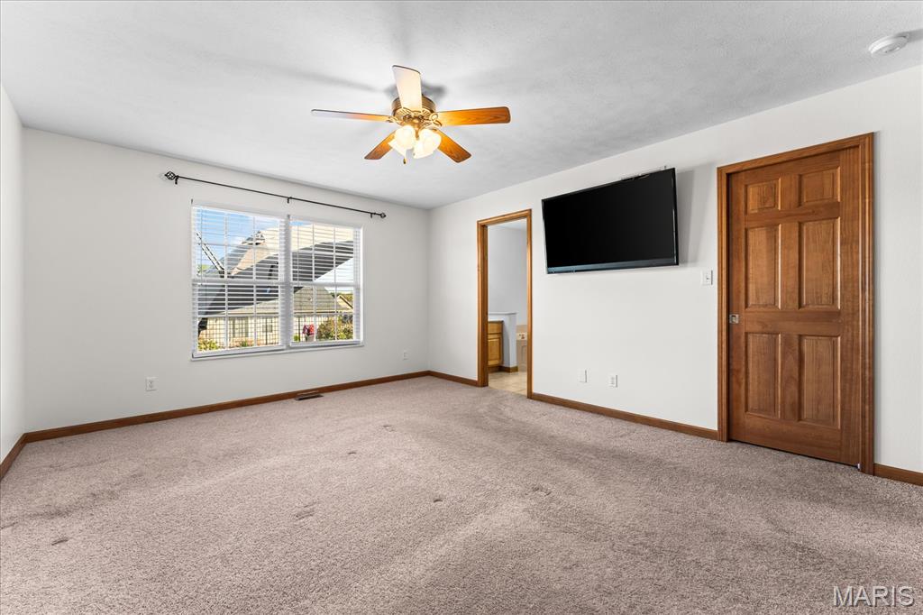 Carpeted bedroom with a ceiling fan, window with blinds, and wall-mounted television.