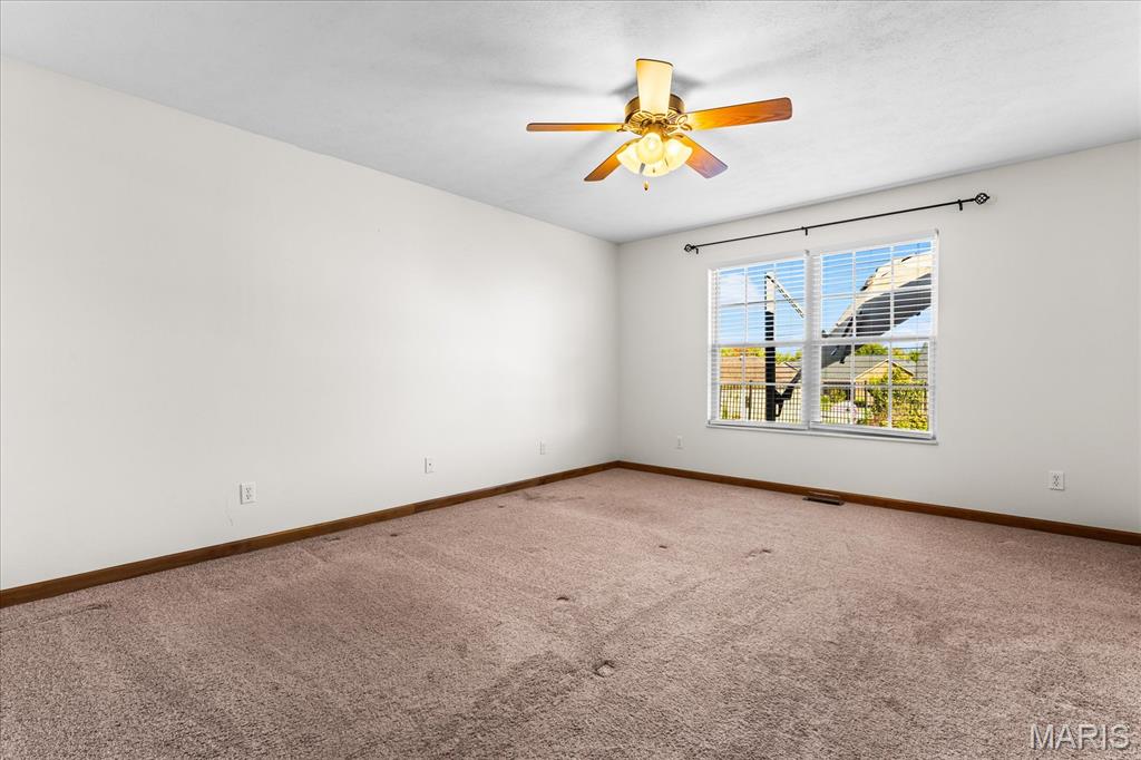 Empty carpeted room with a ceiling fan and a window with blinds.