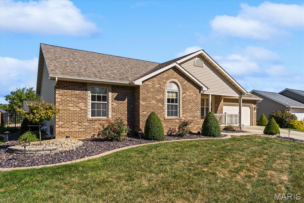 Single-story brick home with an arched front window, covered porch, and attached garage.